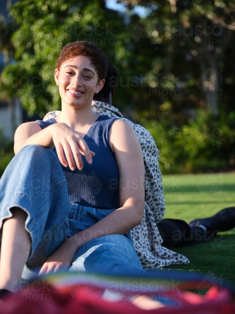 Man and woman sitting back-to back in park - Australian Stock Image