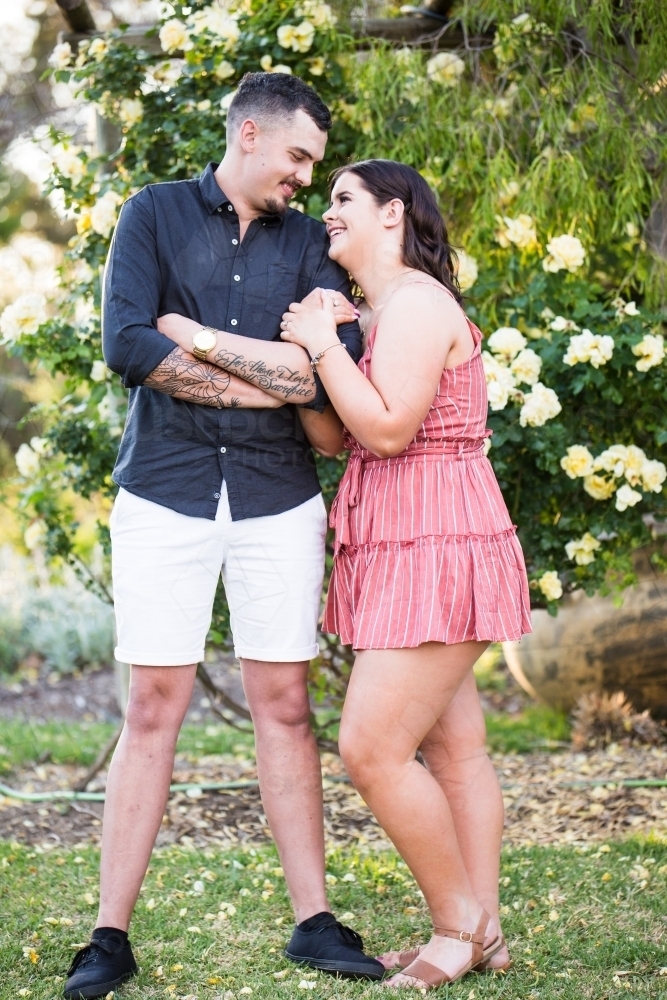 Man and woman snuggling up looking at each other smiling in love - Australian Stock Image