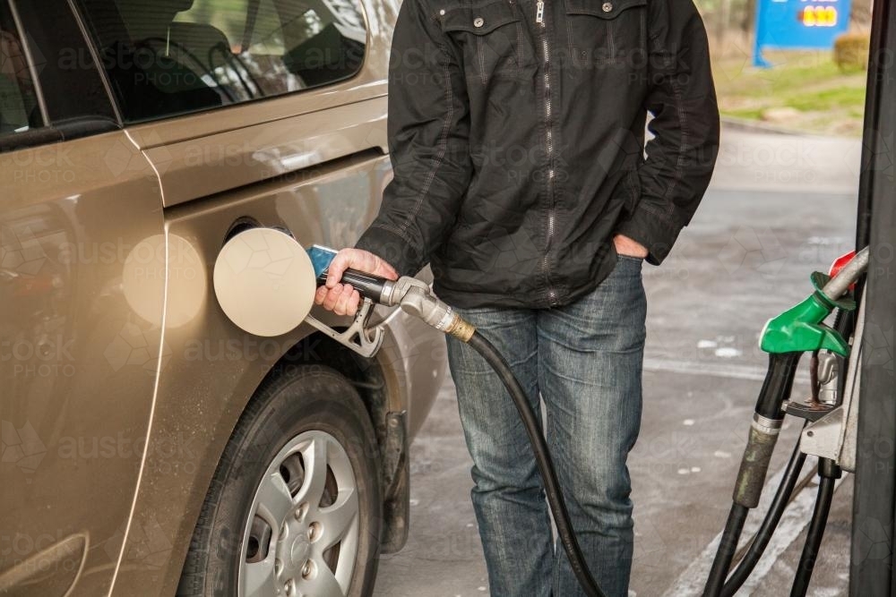 Man at petrol station filling up family car with fuel - Australian Stock Image