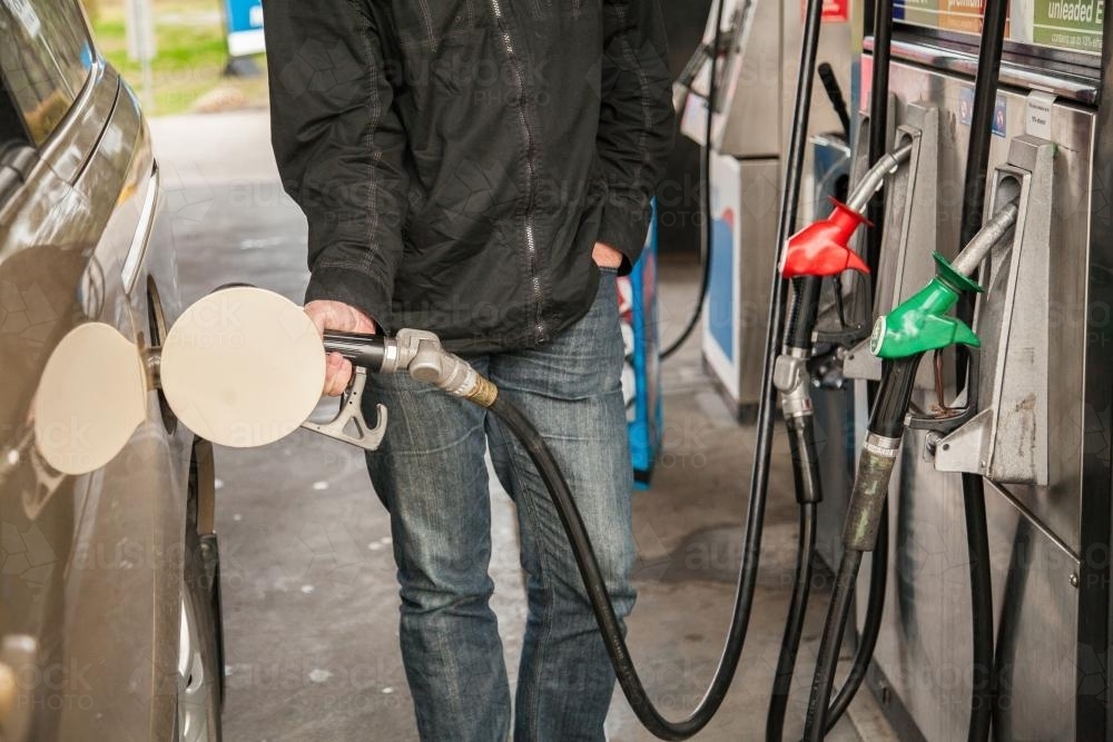 Man at petrol station filling up family car with fuel - Australian Stock Image