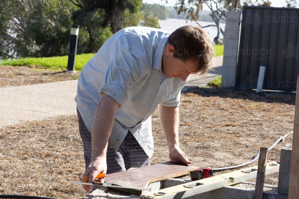 Man bending over diy project outdoors - Australian Stock Image