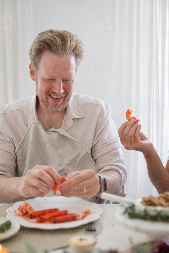 Man deveining prawn at dinner table - Australian Stock Image