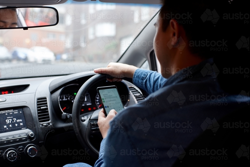 Man driving in his car whilst texting - Australian Stock Image