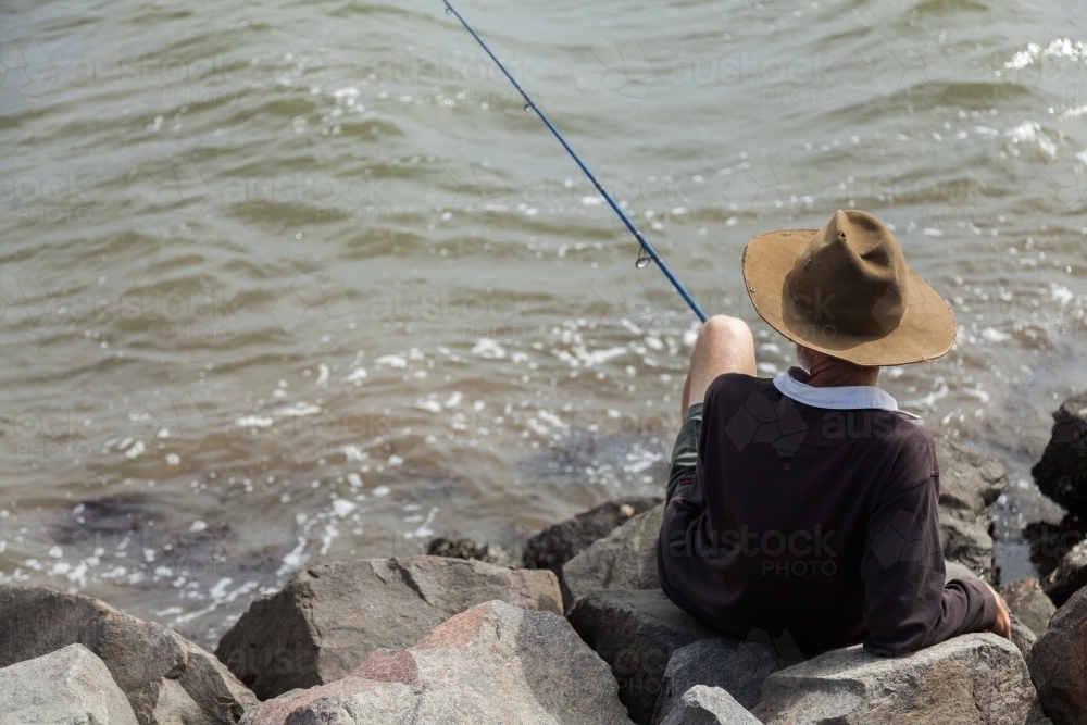 Image of Child holding a yellow fishing rod over water - Austockphoto