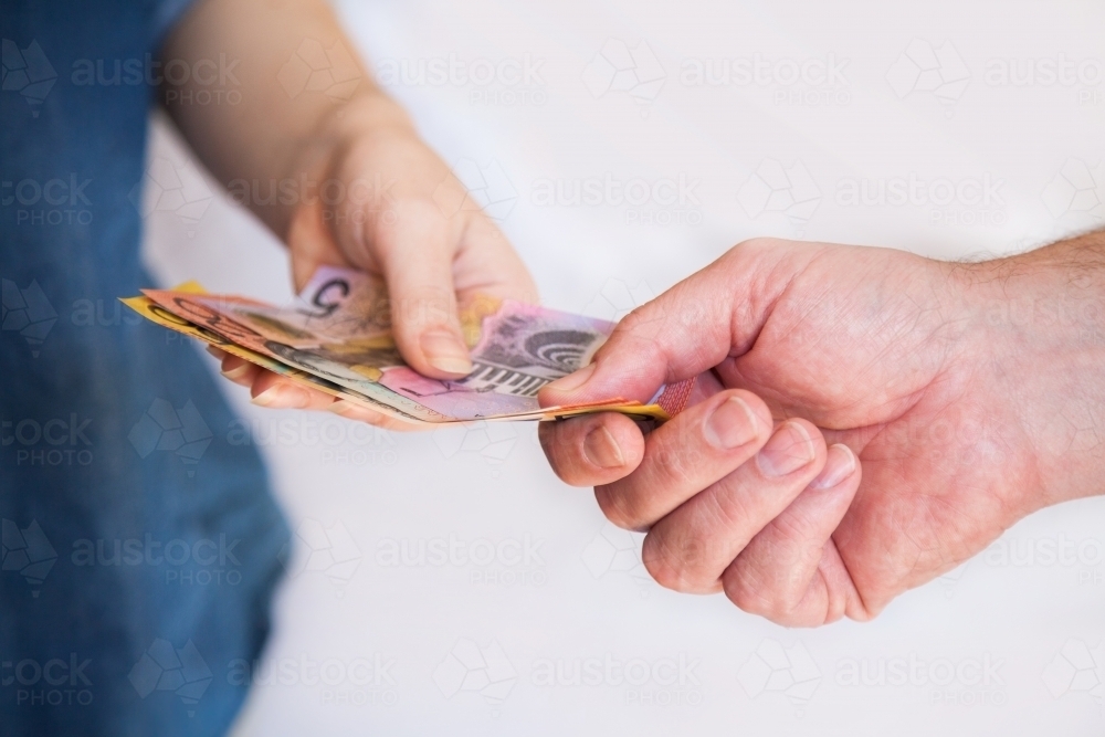 Man handing cash to a woman five dollar note of australian currency - Australian Stock Image