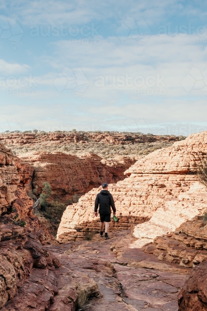 Man hiking over rocks in the outback. - Australian Stock Image