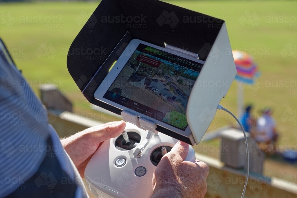 Man holding a white controller with aerial views visible flying his drone, uav, rpas - Australian Stock Image