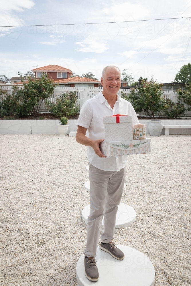 Man holding Christmas presents in front yard - Australian Stock Image
