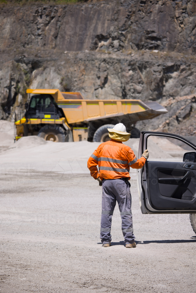 Man in high visibility clothing opening the door of his car. - Australian Stock Image