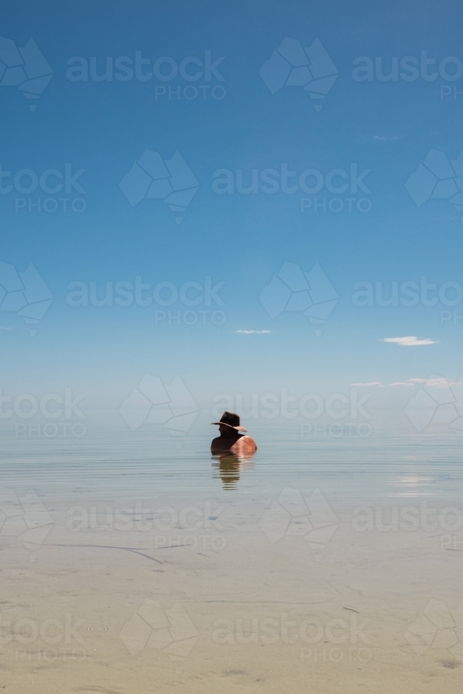 man in the ocean wearing akubra hat - Australian Stock Image