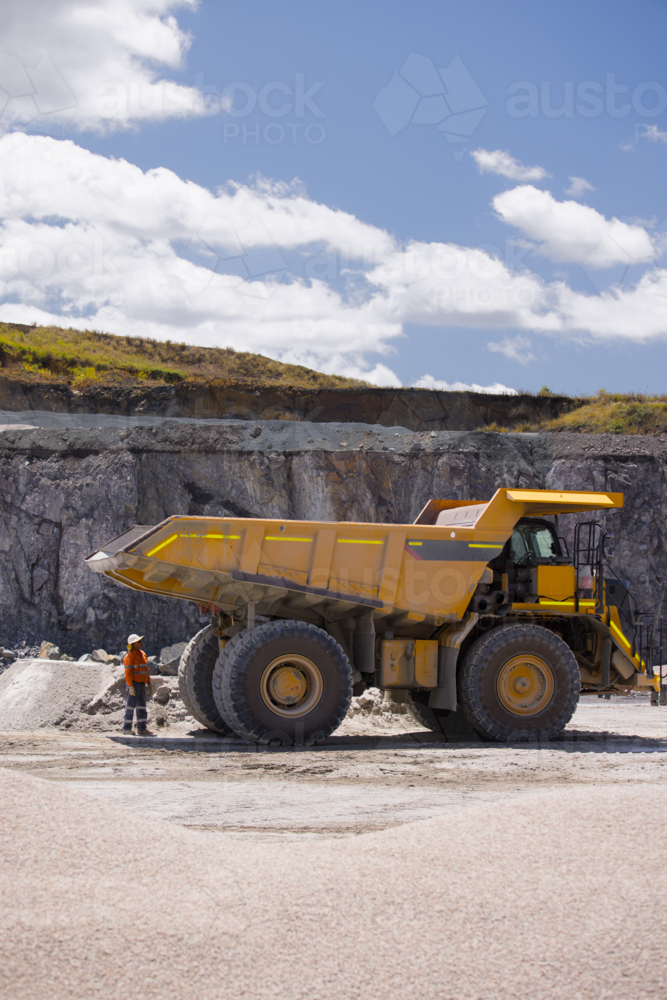 Man in workwear checking the back end of the hauler dump truck on mine site - Australian Stock Image