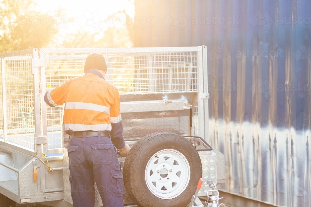 Man in workwear getting tools from trailer lockbox - Australian Stock Image