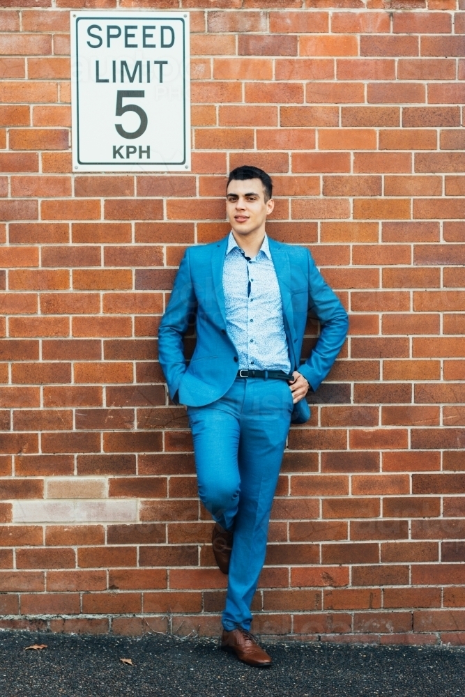 man leaning against wall with speed limit sign - Australian Stock Image