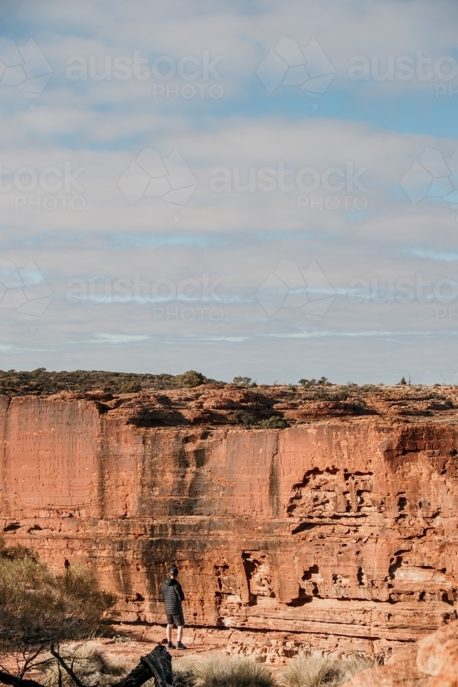 Man looking towards cliff face in the outback. - Australian Stock Image