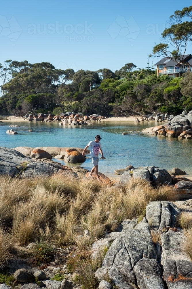 Man on boulder rocks at beach - Australian Stock Image