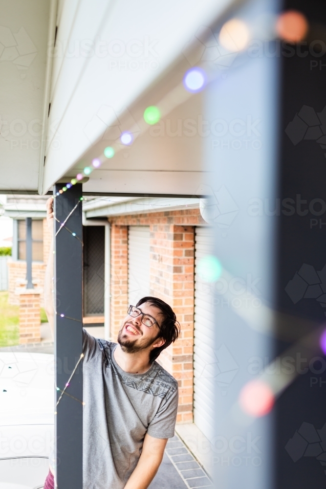 Man putting up smart led Christmas lights on front of home - Australian Stock Image