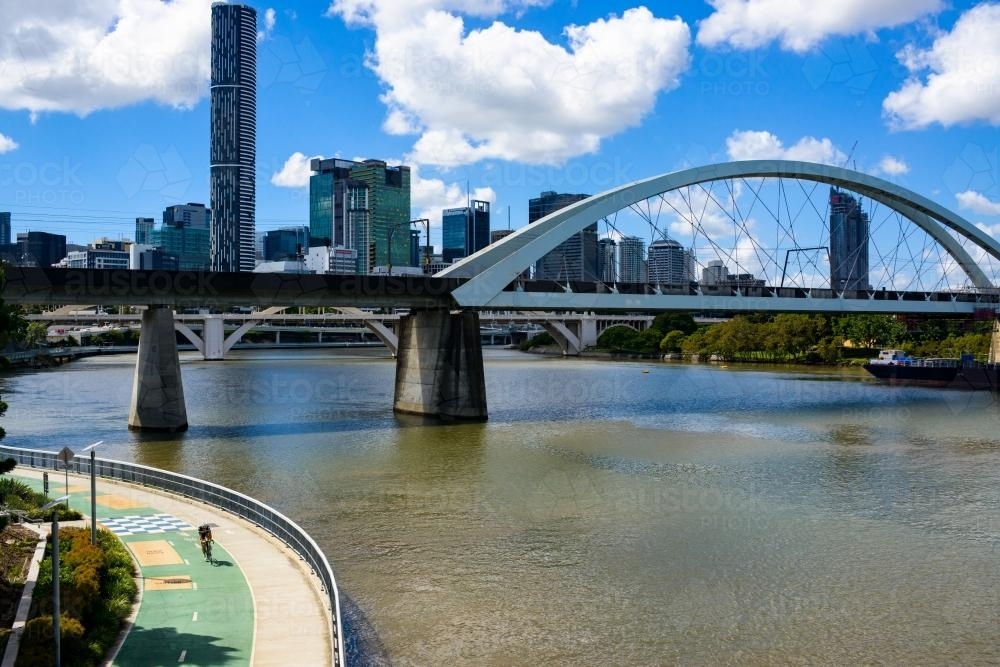 Image of Man riding bicycle on riverside bikeway with bridges in ...