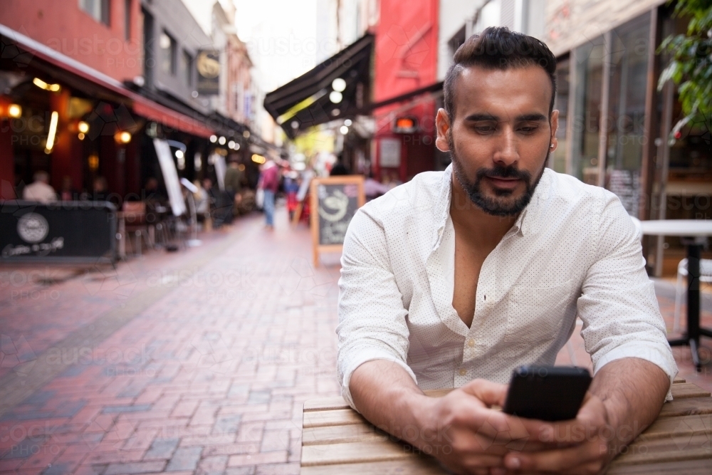 Man Sitting and Texting in Hardware Lane - Australian Stock Image