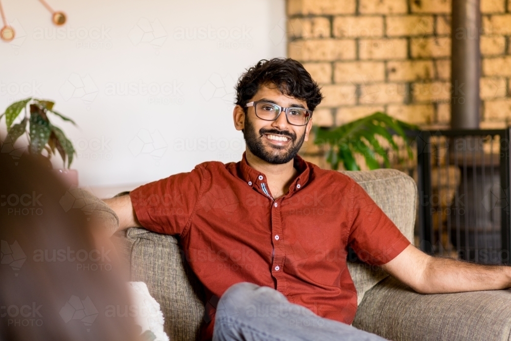 man sitting on couch talking with his partner - Australian Stock Image