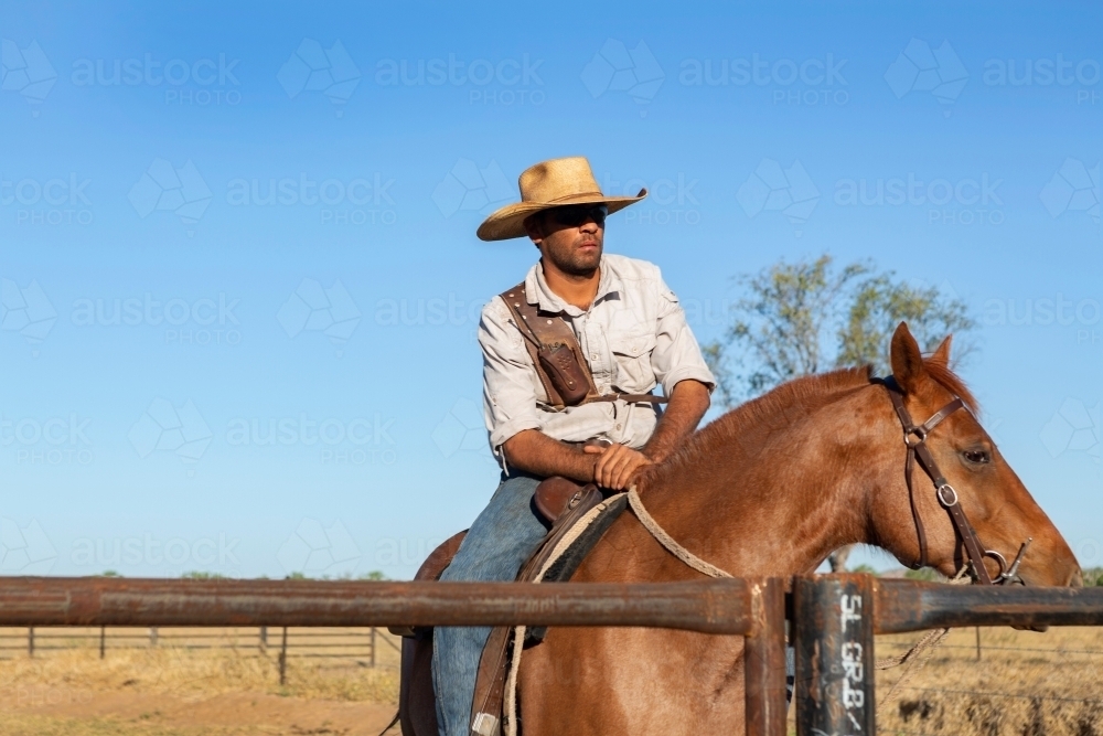 Man sitting on his horse at fence - Australian Stock Image