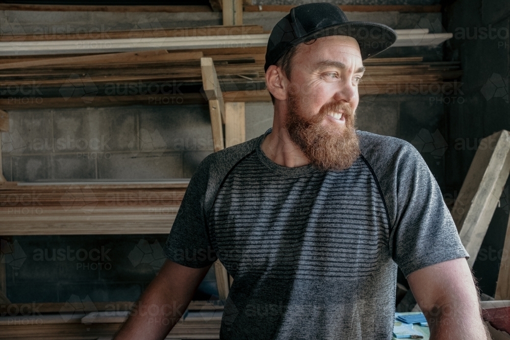 Man smiles and looks sideways in a workshop. - Australian Stock Image