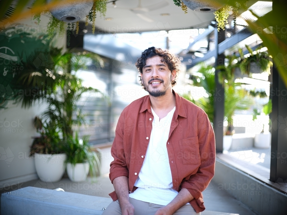 Man smiling in plant-filled room interior - Australian Stock Image