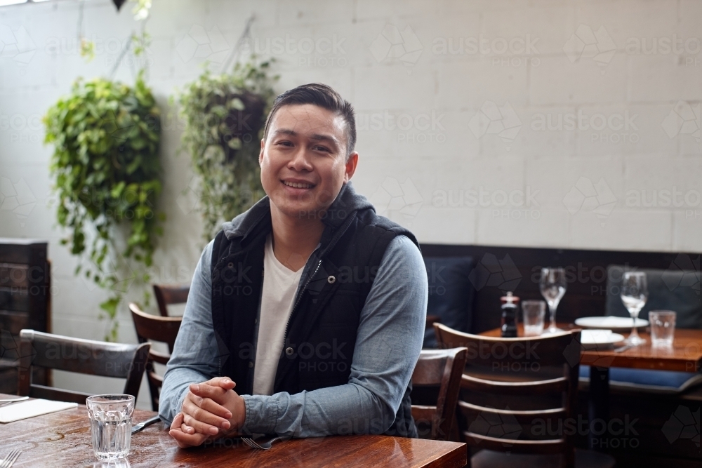 Man smiling sitting at table at cafe - Australian Stock Image