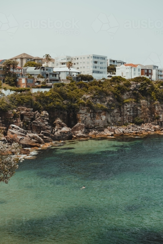 Man swimming in the idyllic clear water at Gordons Bay. - Australian Stock Image