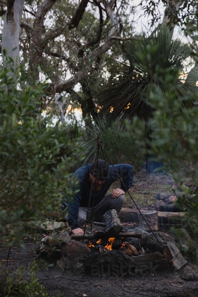 Man tending to camp fire - Australian Stock Image