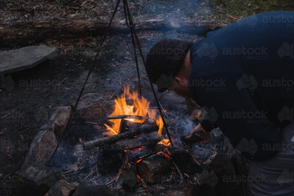 Man tending to camp fire - Australian Stock Image