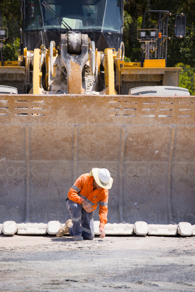 Man tightening the bolts on the bucket of a payloader. - Australian Stock Image