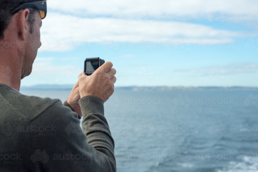 Man using GoPro video camera on boat - Australian Stock Image