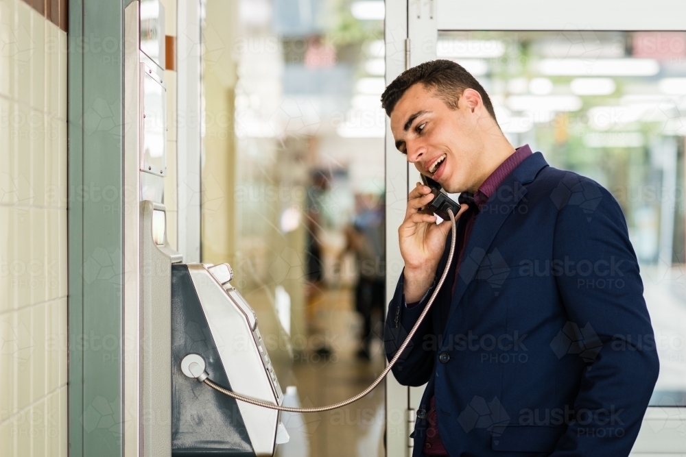 man using payphone at the train station - Australian Stock Image