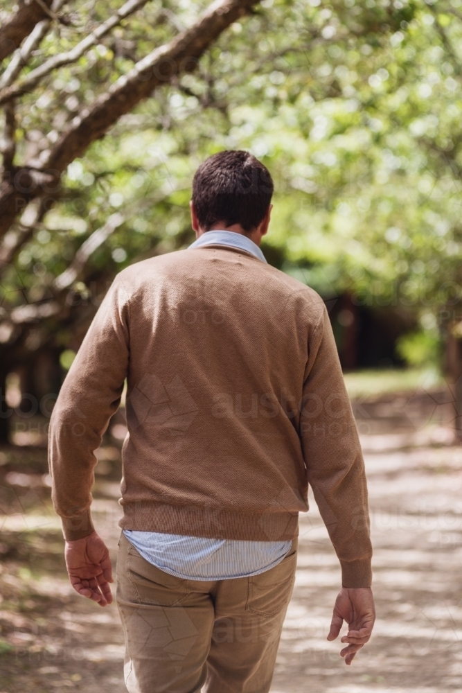 man walking down a treelined path - Australian Stock Image