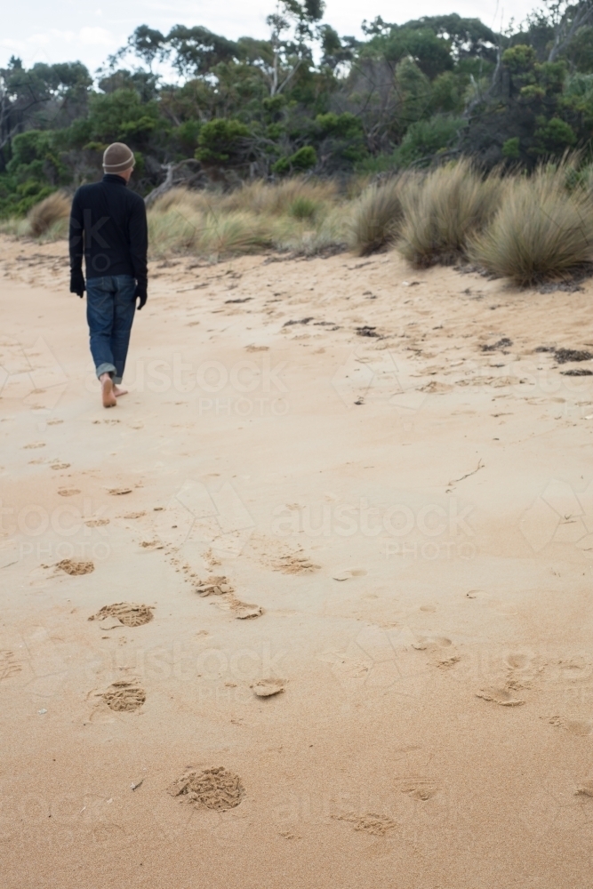 Man walking on beach on winter day - Australian Stock Image