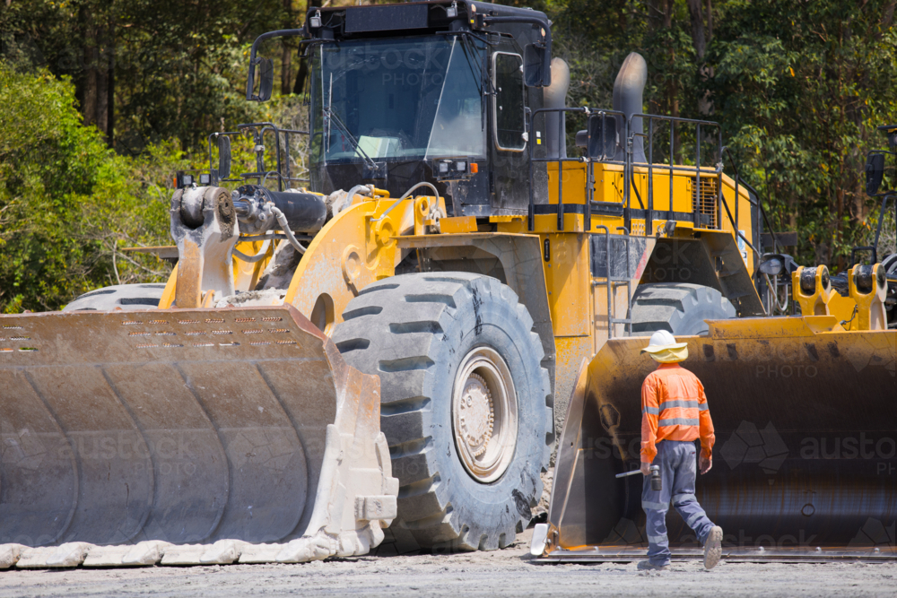 Man walking towards payloader truck on a sunny day. - Australian Stock Image