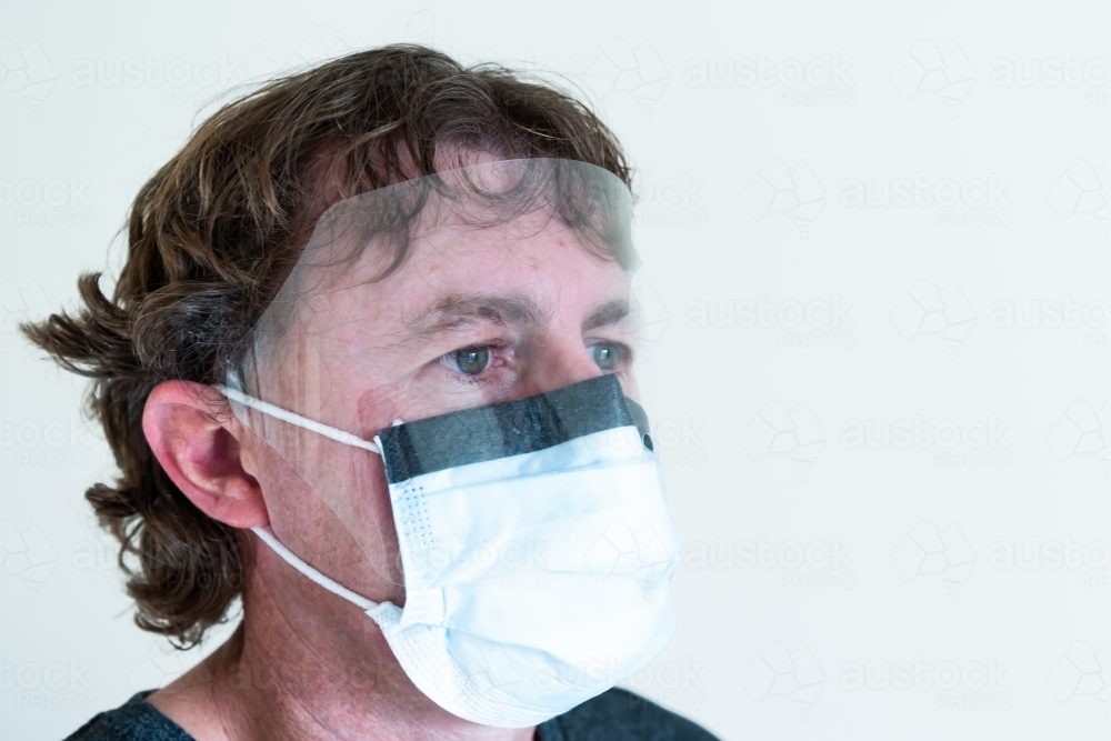 Man wearing surgical mask with eye shield - Australian Stock Image