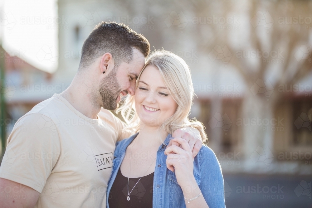 Man with arm around girlfriend's shoulder heads close together - Australian Stock Image