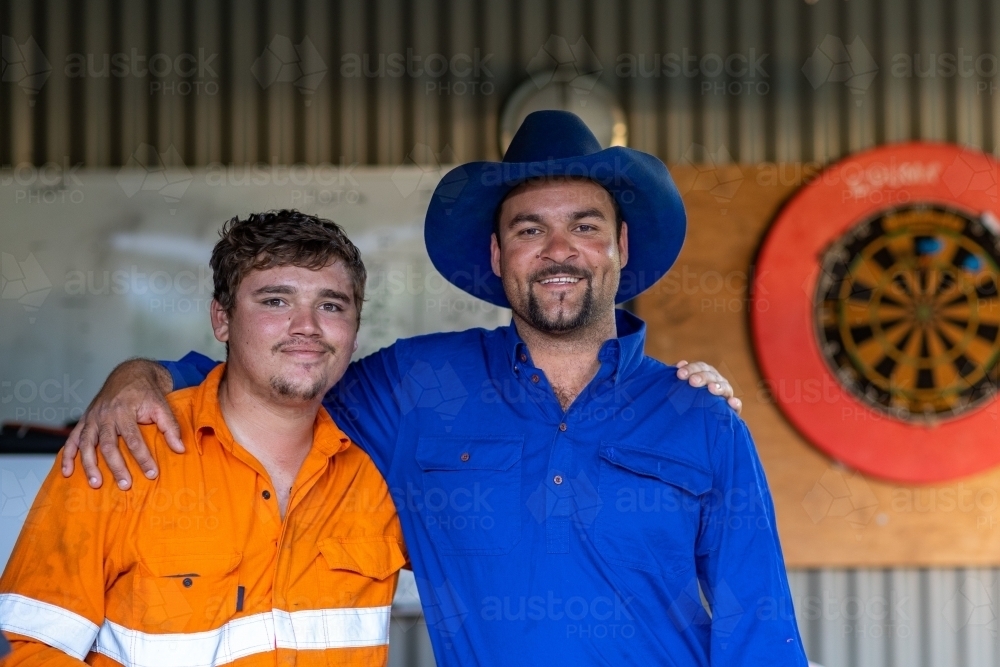 man with arm around shoulder of younger man in tradie shirt - Australian Stock Image