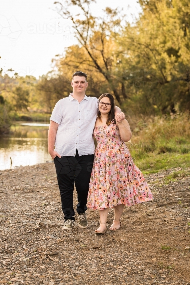 Man with arm around woman's shoulders walking and smiling - Australian Stock Image