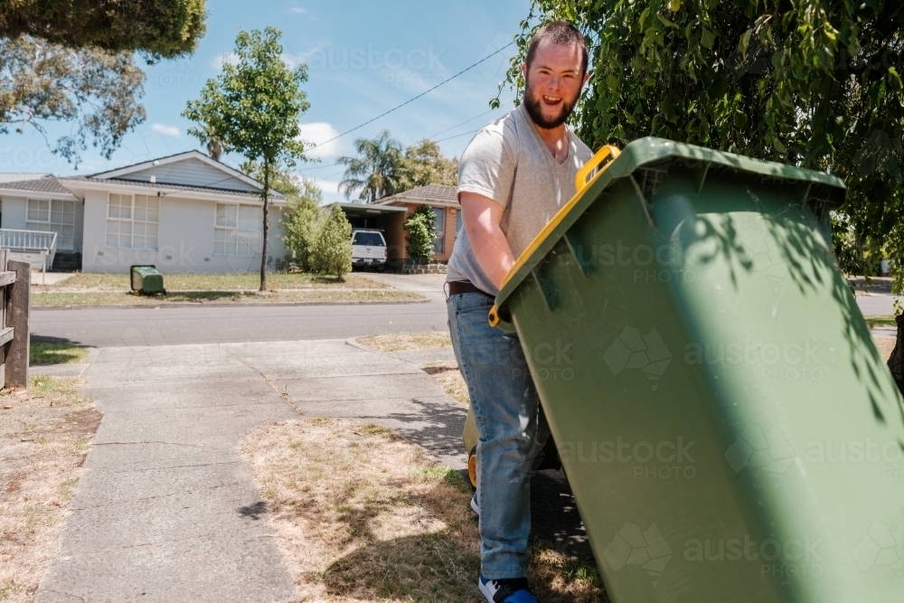 Man with Down Syndrome Bringing In Wheely Bin - Australian Stock Image