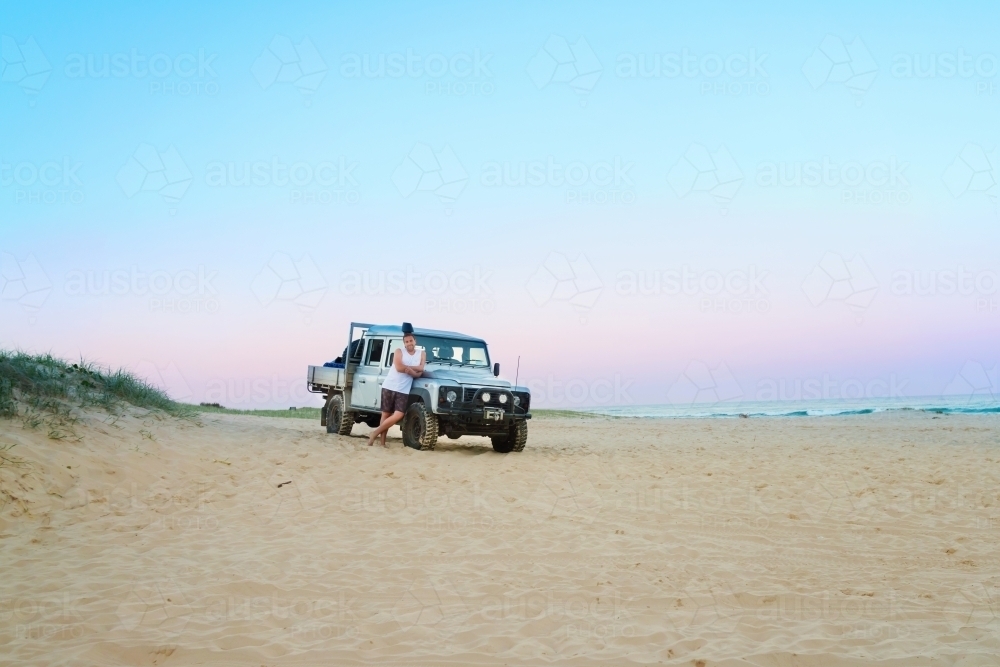 man with his 4x4 on the beach at sunset - Australian Stock Image