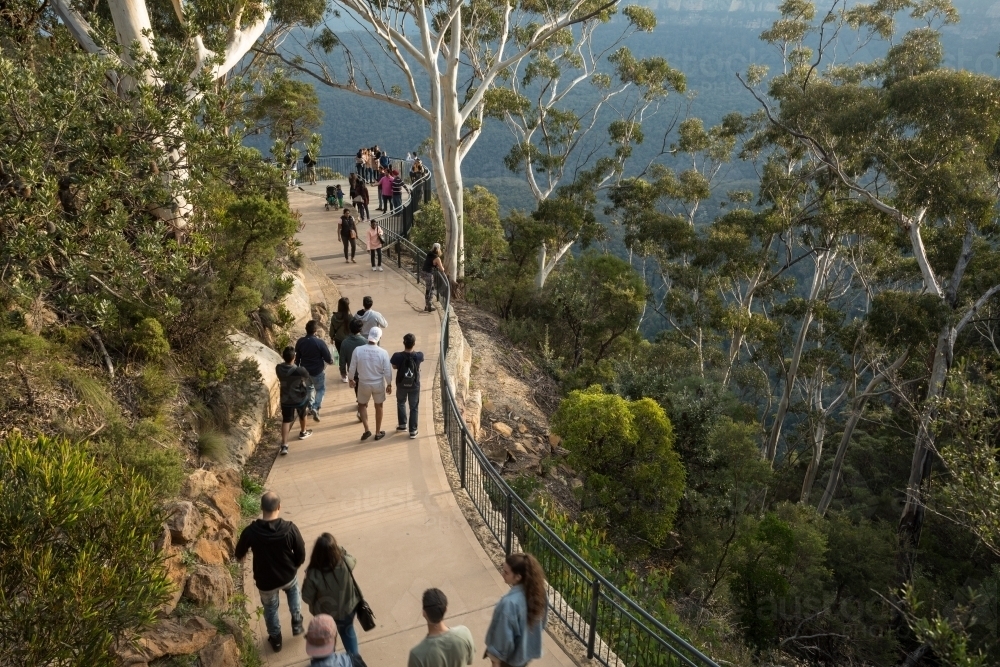 Many tourists walking on concrete pathway through bushland, viewed from above - Australian Stock Image