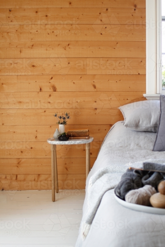 Marble bedside table with timber wall, grey bed linen and wool - Australian Stock Image