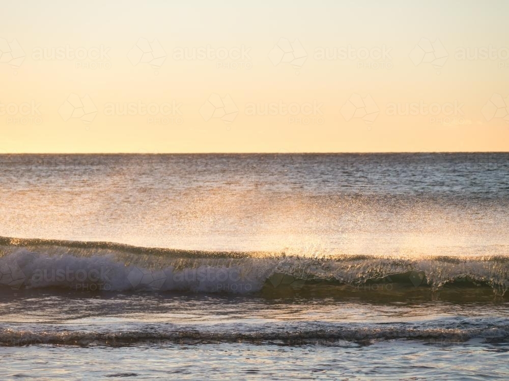 Mare's tail on a ocean wave with sun behind - Australian Stock Image