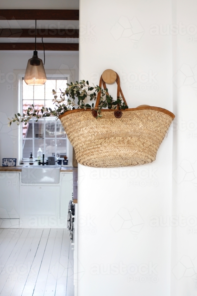 Market basket with eucalyptus leaves hanging on white wall with kitchen background - Australian Stock Image