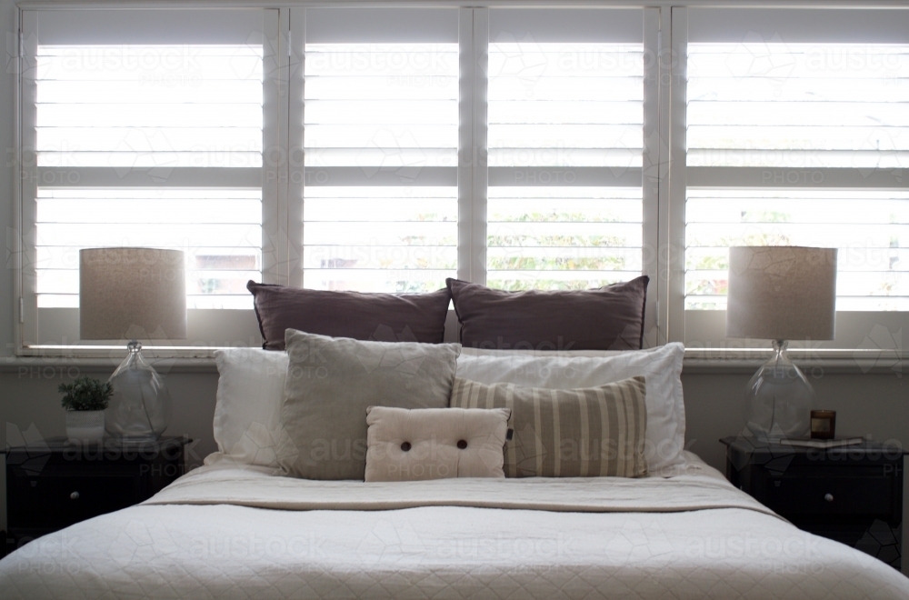 Master bedroom with bed, bedside tables and shutters - Australian Stock Image