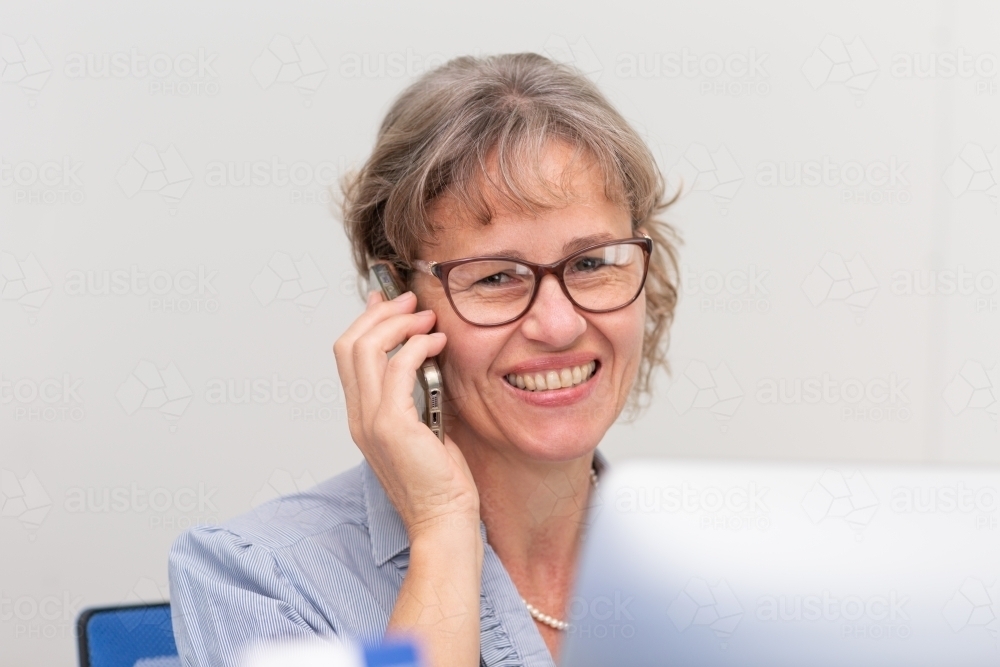 Mature business woman holding phone to ear - Australian Stock Image