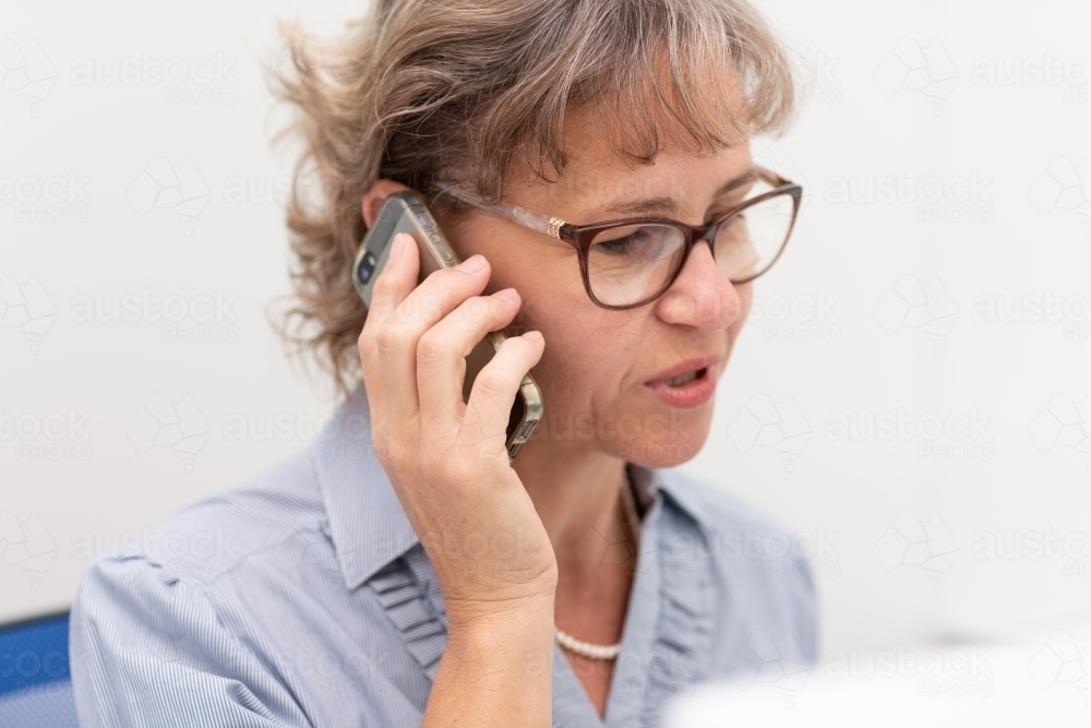 Mature business woman holding phone to ear - Australian Stock Image