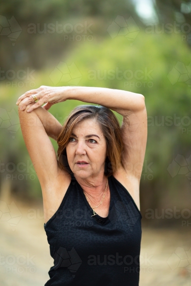 Mature woman doing arm and shoulder stretching exercises - Australian Stock Image